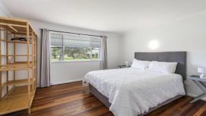 a bedroom with a bed and a window at Twin Palms Retreat in Wooli