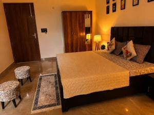 a bedroom with a large bed and two stools at Cozy and Tranquil nest with wifi and homely care in Greater Noida