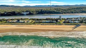 an aerial view of a beach with houses and the water at The Peninsula Wooli in Wooli