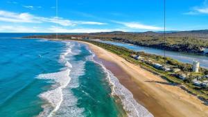 an aerial view of a beach and the ocean at The Peninsula Wooli in Wooli