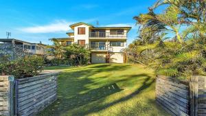 an exterior view of a large house with palm trees at The Peninsula Wooli in Wooli +13 photos