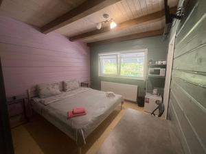a small bedroom with a bed with a pink wall at Кольорове життя in Mykulychyn