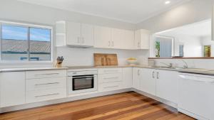 a white kitchen with white cabinets and a window at Sea Legs in Wooli