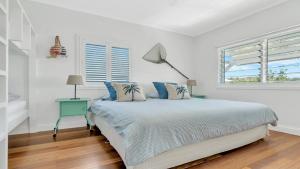 a white bedroom with a bed and a window at Sea Legs in Wooli