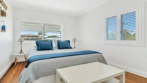 a bedroom with a bed with blue pillows and a window at Sea Legs in Wooli