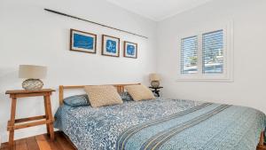 a bedroom with a bed with a blue comforter and two windows at Sea Legs in Wooli +6 photos
