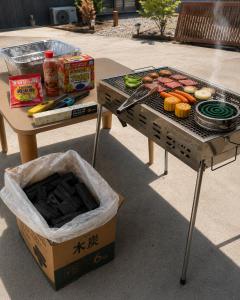 ein Tisch mit einem Grill und ein Tisch mit Essen darauf in der Unterkunft Smith 夫婦 in Setouchi