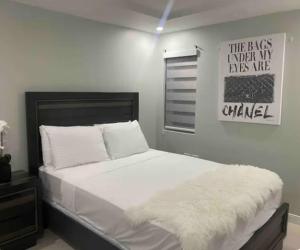 a bedroom with a bed with a white blanket on it at The Grand suite in Portmore +9 photos