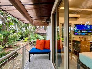 a porch with a bench and a tv on a balcony at The Snug & The Sierra Airportel in Nai Yang Beach