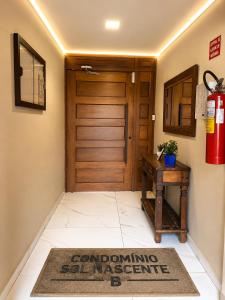 aoyer with a wooden door and a table and a rug at Roupa cama Wi-Fi garagem ar Cond beira mar 50 m in Tramandaí