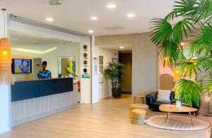 a man standing behind a counter in a lobby at Hôtel du Centre Appart hôtel Business avec Parking Gratuit à Nouméa in Noumea