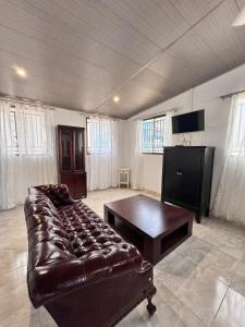 a living room with a leather couch and a flat screen tv at Casa Dulce in Estelí