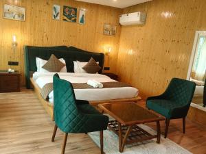a bedroom with a bed and two green chairs at Cottages & Cafe in Dogadda +29 photos