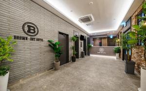 a hallway with plants on a brick wall at Brown Dot Hotel Guun in Suwon
