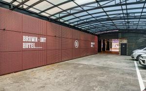 a parking lot with a red wall with a car parked in it at Brown Dot Hotel Guun in Suwon