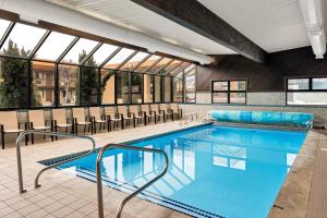 a swimming pool with chairs in a building at Days Inn & Suites by Wyndham Logan in Logan