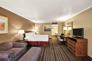 a hotel room with a bed and a desk at Days Inn & Suites by Wyndham Logan in Logan