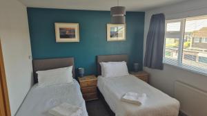 two beds in a room with blue walls at High Tide in Braunton