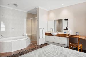 a white bathroom with a tub and a sink at Quality Hotel Bayswater in Perth
