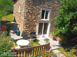 a stone house with a table and chairs and an umbrella at la bergerie in Cronce