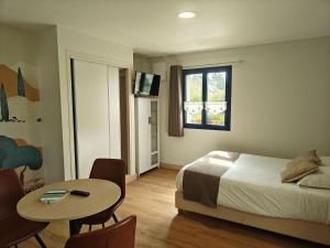 a hotel room with a bed and a table and a tv at Studios - Location de vacances Le Trécelin in Plévenon +31 photos