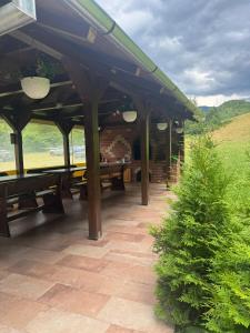 a pavilion with wooden picnic tables on a patio at Hanul Ursilor in Chişcău