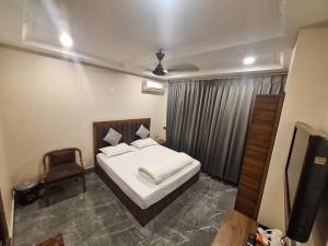 a bedroom with a bed and a chair and a television at Sun Hill Homestay in Siliguri +27 photos