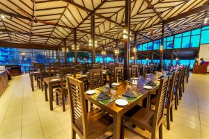 a restaurant with wooden tables and chairs and windows at Citrus Hikkaduwa in Hikkaduwa