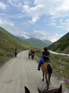 a group of people riding horses down a dirt road at Old House in Ushguli