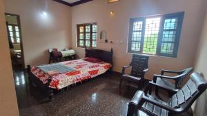 a bedroom with a bed and chairs and windows at Homestay Nandana Full apartment with Kitchenware in Gokarna