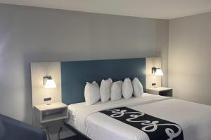 a hotel room with a bed with white pillows at La Quinta Inn by Wyndham Auburn Worcester in Auburn