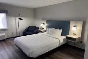 a hotel room with a bed and a blue chair at La Quinta Inn by Wyndham Auburn Worcester in Auburn