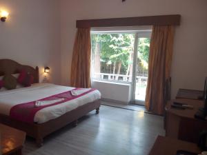 a bedroom with a bed and a large window at Hotel isabel Palace in Khajurāho