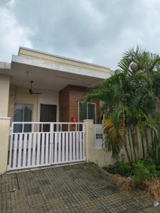 a house with a white fence and a palm tree at The Global Nest Homestay 