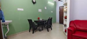a dining room with a table and chairs and a red couch at Eden Cozy Villa in Virāmpattinam