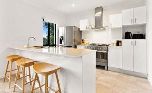 a kitchen with white cabinets and bar stools at Palm Cove Retreat I heated pool I Family home in Palm Cove