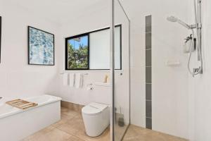 a bathroom with a toilet and a glass shower at Palm Cove Retreat I heated pool I Family home in Palm Cove