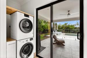 a laundry room with a washer and dryer in a house at Palm Cove Retreat I heated pool I Family home in Palm Cove +43 photos
