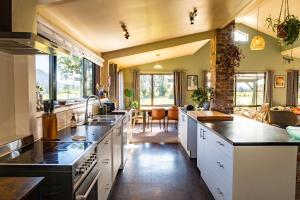 a large kitchen with white cabinets and a large island at Waimanu Guest House in Franz Josef