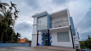 a white and blue house with palm trees at Grace Residency in Sultan Bathery