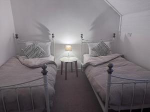 a bedroom with two beds and a table with a lamp at The Studio Cottage in Denbigh