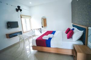 a bedroom with a bed and a table and a tv at Grace Residency in Sultan Bathery