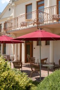 a patio with red umbrellas in front of a building at Ametiszt Hotel Harkány in Harkány