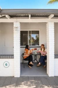 two people sitting at a table on a porch at Busselton Jetty Chalets in Busselton