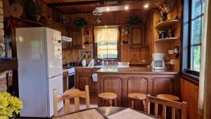 a kitchen with a white refrigerator and wooden cabinets at Domek pod Lasem in Płaska