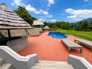 a swimming pool with benches and a pavilion at KuangSi Resort in Luang Prabang