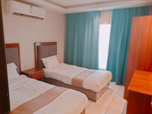 a hotel room with two beds and blue curtains at فندق هدب - المربع in Riyadh +12 photos