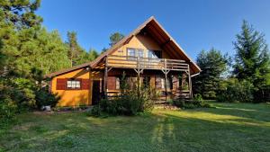 a large wooden house with a large yard at Domek pod Lasem in Płaska