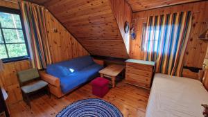 a room with a blue couch and a bed in a cabin at Domek pod Lasem in Płaska