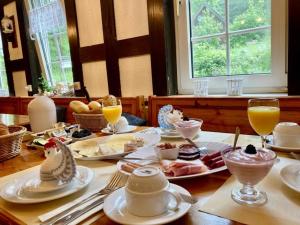 a table with plates of food and glasses of orange juice at Waldhaus Wolfsbachmühle in Hohegeiß